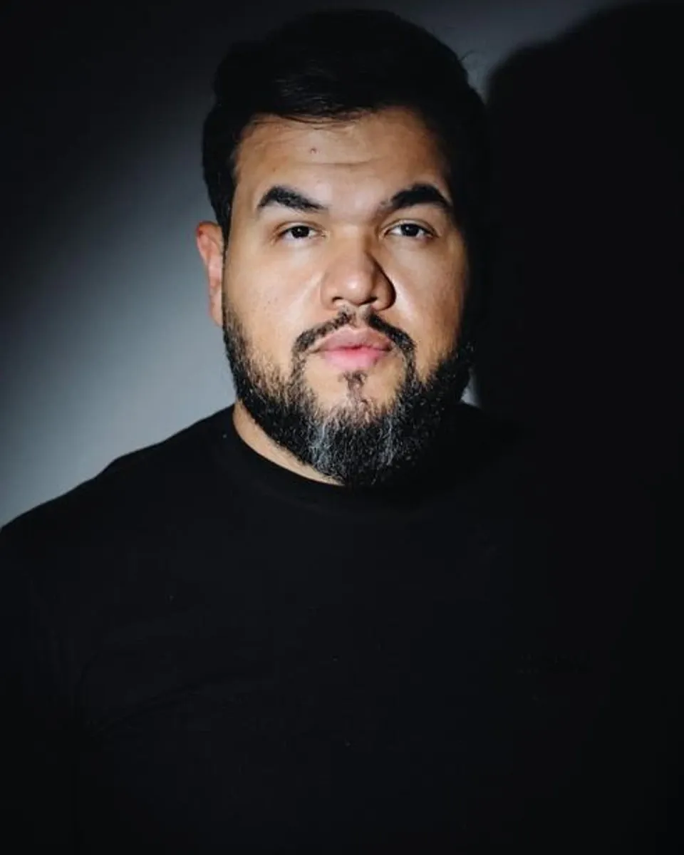 Victor Moura, retrato em camiseta preta sob luz azul